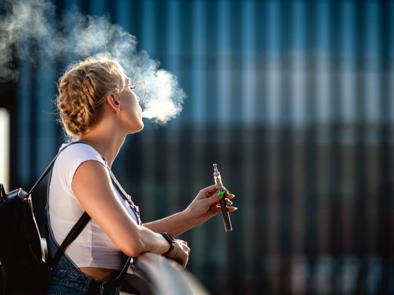 Junge Frau, die eine E-Zigarette raucht